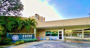 A building with a sign reading 'Zazué Condominium,' a covered entrance, and a gated parking area. - Zazue Beach Apartments by Xarm Apartments (Santa Marta)