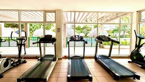 Une salle de sport équipée de tapis de course, de vélos d’appartement et d’un appareil d’aviron.