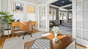 A spacious room with a wooden desk, a comfortable chair, a large window, and a cozy seating area with a sofa and armchairs. - Maine Social House/By Downtown/Balcony (Portland)