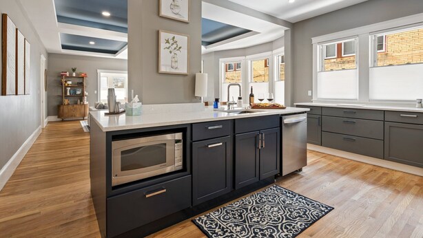 A modern kitchen with dark cabinetry, a central island, and a view of the outside. - Maine Social House/By Downtown/Balcony (Portland)