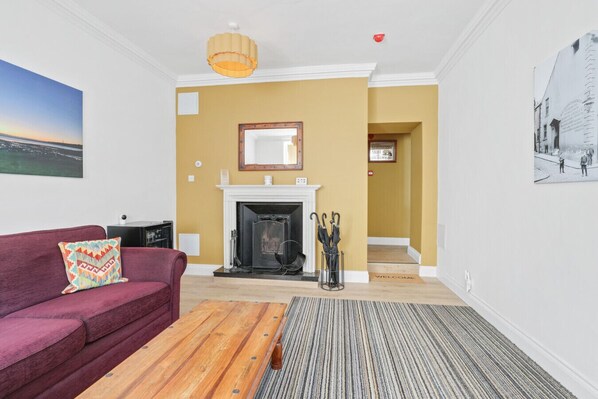 A living room with a fireplace, a sofa, a coffee table, and a hallway leading to another room.