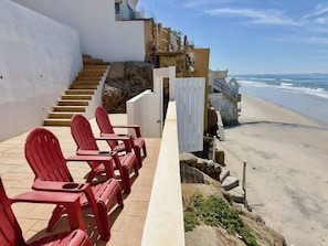 Un hotel costero con sillas rojas, una escalera y vista a la playa.