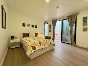 Un dormitorio con cama, mesita de noche y vistas al exterior a través de un ventanal corredero.