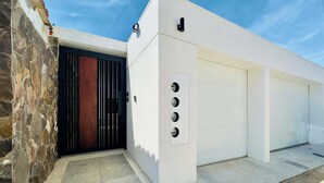 Een modern gebouw met een stenen muur, een zwart hek en een garage met vier deuren.