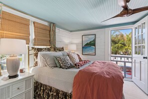 A bedroom with a bed, bedside table, lamp, and a ceiling fan. - Two Palms Cottage on St Simons (St Simons Island)