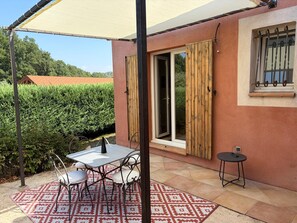 A patio with a table and chairs, a small round table, and a window with a metal grill. - Private Pool • Sillan Waterfall • Verdon • Nature Vacations in Provence (Sillans-la-Cascade)