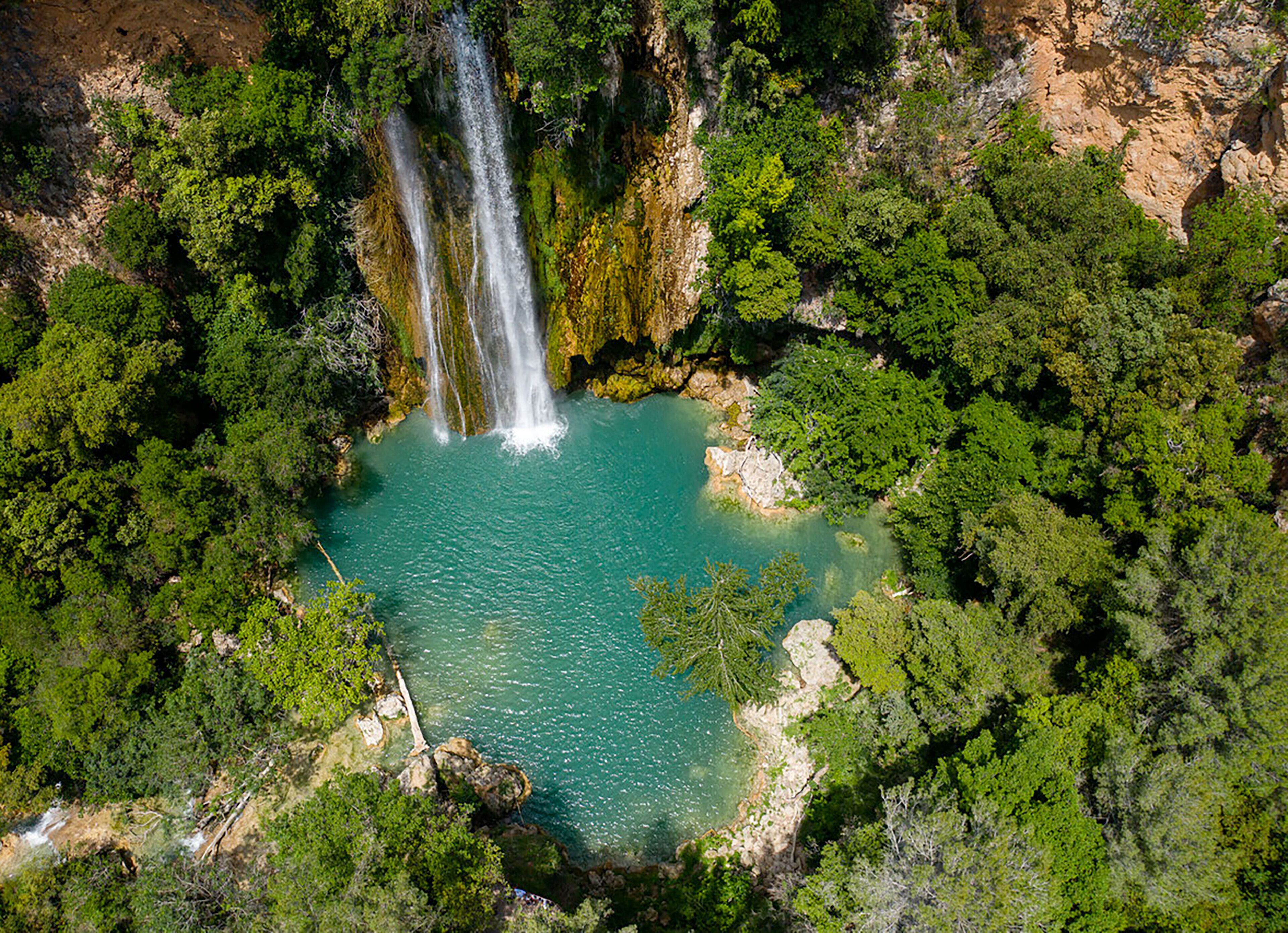 Una cascata circondata da una fitta vegetazione verde.