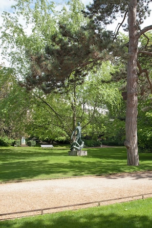 A park with a statue, a bench, and a tree. - Akila Apart City - Place du Panthéon (Paris)