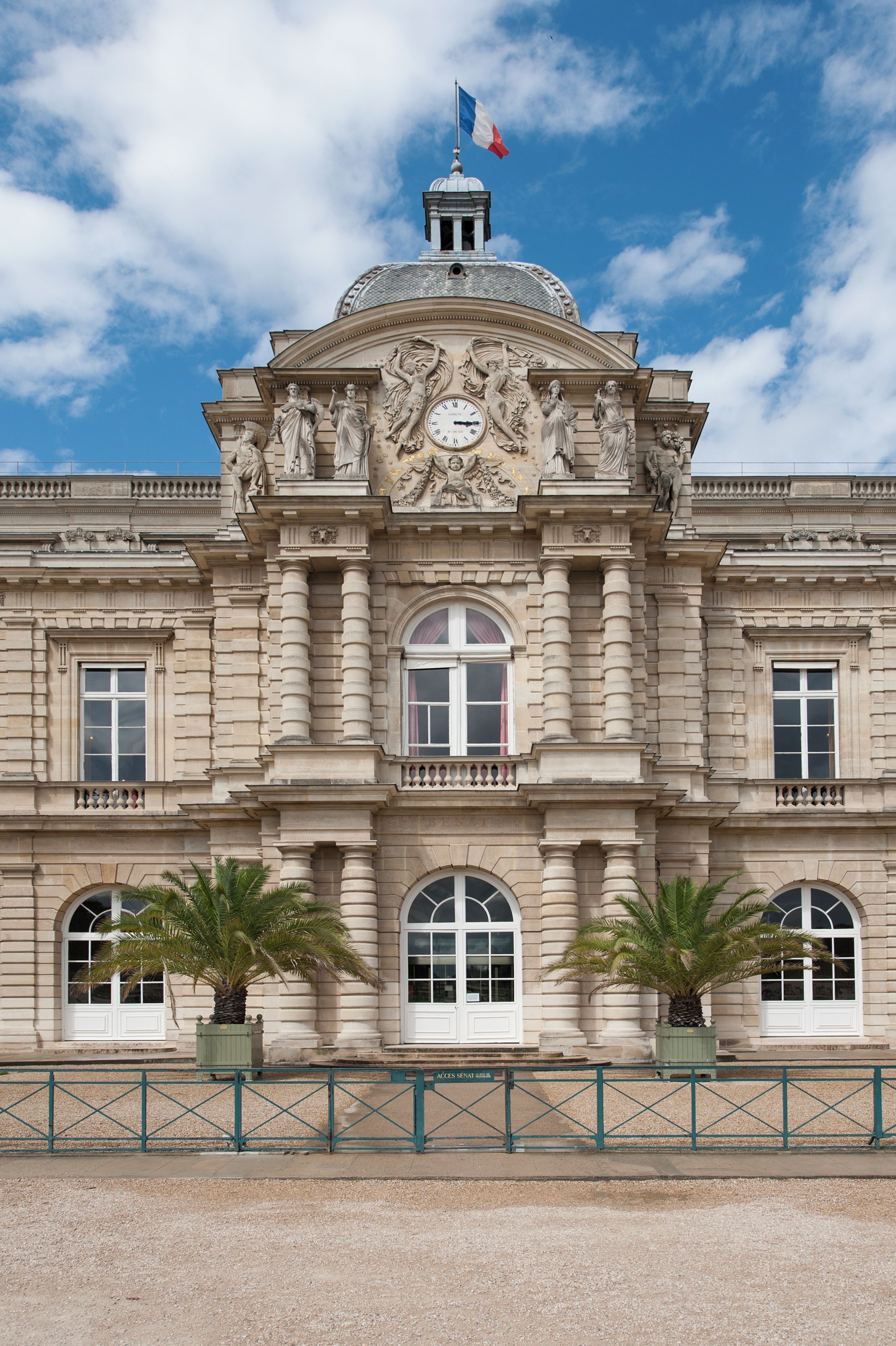 A historic building with classical architecture, featuring a prominent clock, statues, and a dome.