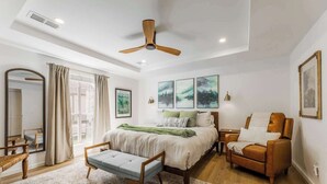 A bedroom with a bed, a chair, a desk, a mirror, and a ceiling fan. - The Cousins House, private pool, prime location (Rogers)