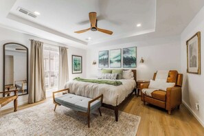 A bedroom with a bed, a chair, a desk, a mirror, and a ceiling fan. - The Cousins House, private pool, prime location (Rogers)