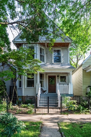 A two-story house with a front porch, a mailbox, and a small garden. - Jan 2027 open ! A-ville Historic Apt w/ Office (Chicago)