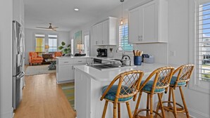 Una cocina moderna con armarios blancos, una isla central y taburetes de bar.