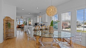 Una cocina moderna con armarios blancos, una mesa de comedor de vidrio y sillas transparentes.