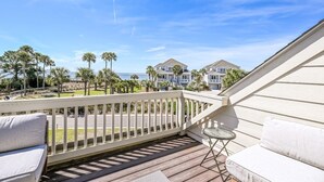 A wooden deck with a white railing, a small round table, and a sofa. - Seabrook Exclusives | 702 Spinnaker Beach (Seabrook Island)
