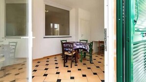Ein Essbereich mit Tisch, Stühlen, einem Fenster und einem Fliesenboden.