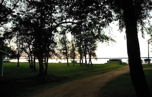 A park with trees, a path, and a body of water in the background.