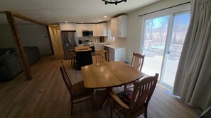 Eine moderne Küche mit weißen Schränken, einem Edelstahlkühlschrank und einem Essbereich mit Holztisch und -stühlen.