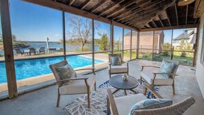 Un patio techado con piscina, mobiliario exterior y vistas al océano.