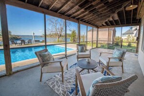 A covered patio with a pool, outdoor furniture, and a view of the ocean.