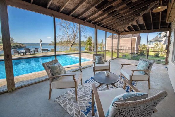 A covered patio with a pool, outdoor furniture, and a view of the ocean.