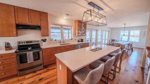 Una cocina moderna con armarios de madera, horno de acero inoxidable, una isla grande con taburetes y ventanas amplias.