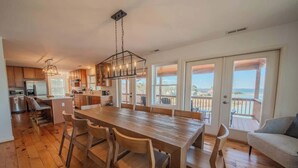 Una cocina amplia con una gran mesa de comedor, sillas de madera y vistas a través de puertas corredizas de vidrio.