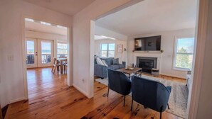 Un salón amplio con chimenea, una mesa de comedor con sillas y un balcón con vistas.