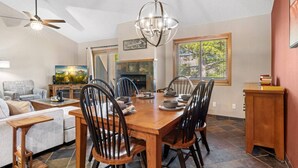 A dining area with a wooden table, black chairs, a chandelier, and a fireplace.