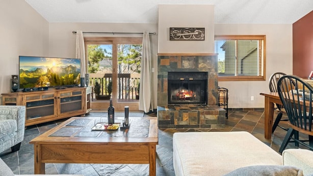 A living room with a fireplace, a television, and a dining area with chairs.