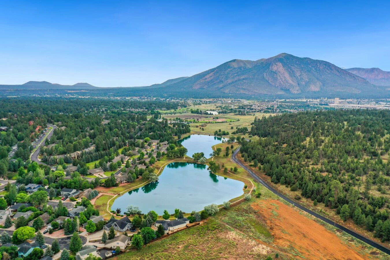 Un quartier résidentiel avec un lac, entouré de maisons et avec une montagne en arrière-plan.