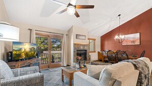 A living room with a fireplace, a television, and a dining area with chairs and a table.