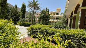 A courtyard with a building featuring arches and a palm tree. - Hotel Pushkar Heritage (Pushkar)