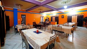 A dining area with tables and chairs, a ceiling fan, and a wall-mounted air conditioning unit. - Hotel Pushkar Heritage (Pushkar)