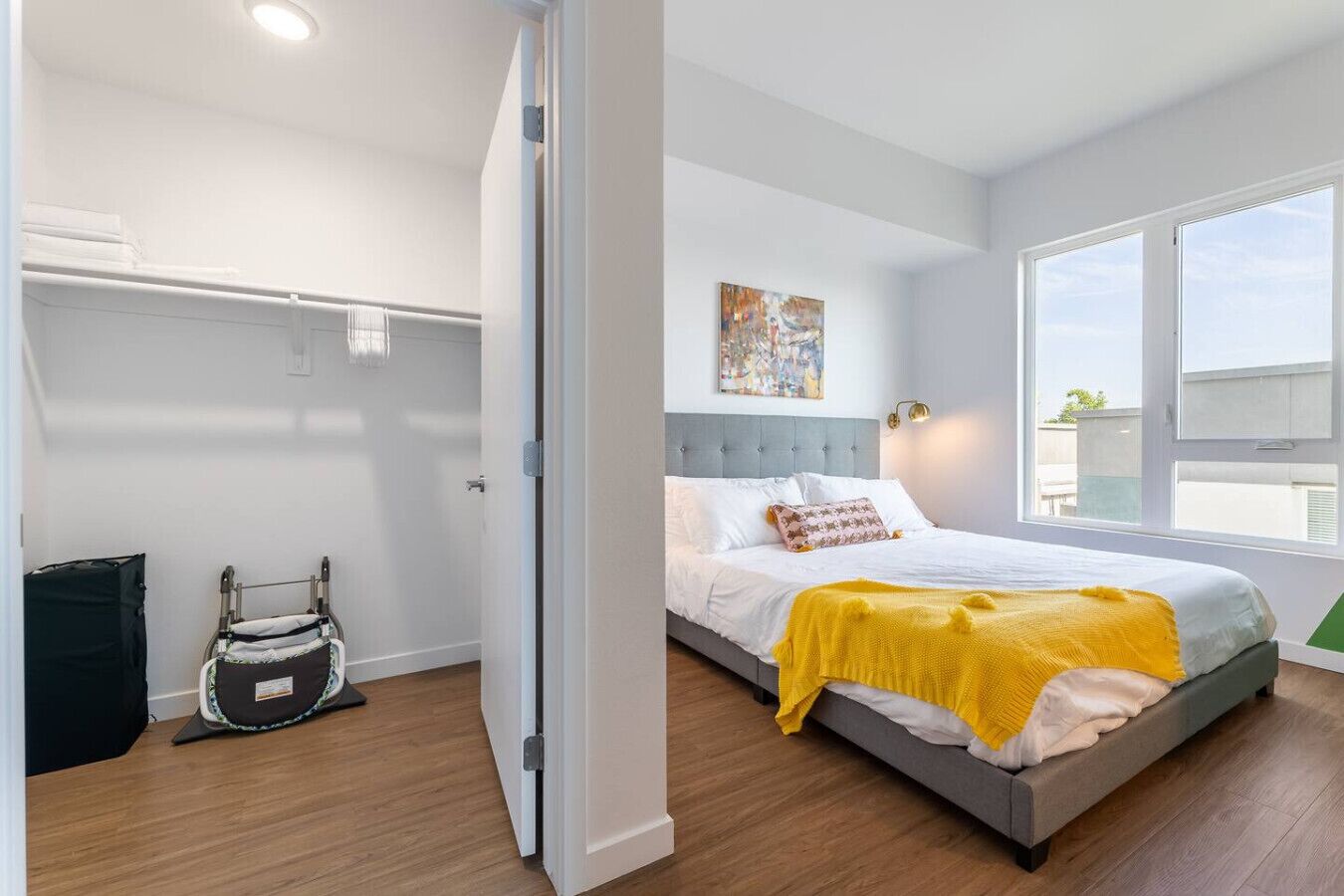 Um quarto moderno com uma cama, mesa de cabeceira, janela e porta.