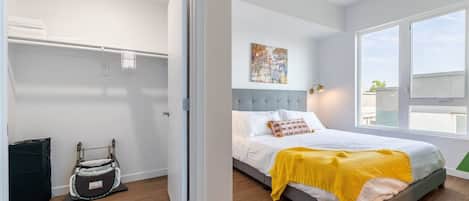 Um quarto moderno com uma cama, mesa de cabeceira, janela e porta.