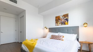A bedroom with a bed, a painting, and a nightstand.