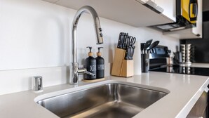 A modern kitchen with a stainless steel sink, a faucet, and a knife block.