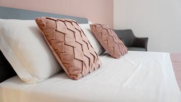 A bed with white bedding and two textured pillows.