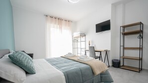Une chambre à coucher comprenant un lit, un bureau, une chaise, un téléviseur et une étagère.