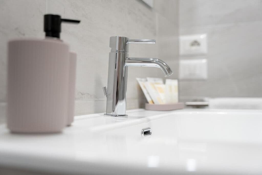 Une salle de bain moderne avec un robinet chromé, un distributeur de savon et un lavabo blanc.