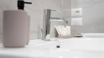 Une salle de bain moderne avec un robinet chromé, un distributeur de savon et un lavabo blanc.