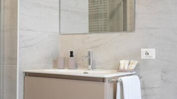 Un baño con lavamanos blanco, un espejo, una toalla y artículos de aseo en la encimera.