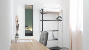 A bunk bed with a mirror, a desk with a chair, and a window with curtains.