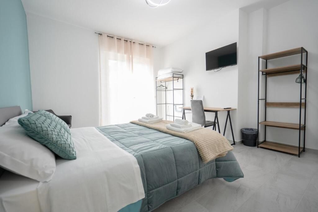 A bedroom with a bed, a desk, a chair, a TV, and a wardrobe.