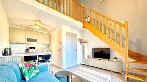 Un salon moderne avec un canapé, une table basse, un téléviseur et un escalier.