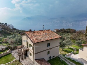 Ein zweistöckiges Gebäude mit einem Ziegeldach, einem kleinen Balkon und Blick auf die Berge im Hintergrund.