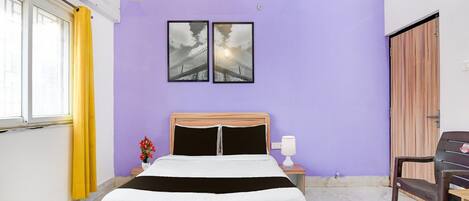 A bedroom with a bed, a nightstand, a chair, a window with yellow curtains, and two wall-mounted lights.