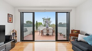 A modern living room with a sliding glass door leading to an outdoor patio area. - Tide & Town - Perfectly Located! (Inverloch)
