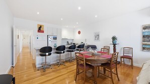 A modern kitchen with white cabinets, a refrigerator, and a clock on the wall. - Tide & Town - Perfectly Located! (Inverloch)